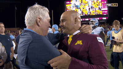 Two Men Hugging In Front Of Fox CFB Screen GIF