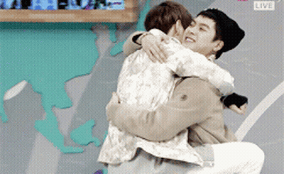 Two Men Hugging In Front Of Live Screen GIF
