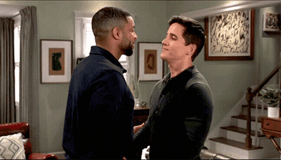 Two Men Hugging In Living Room With Staircase GIF