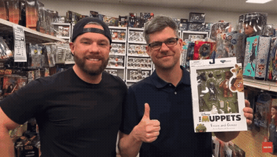 Two Men In A Store Holding A Box Of Muppets GIF