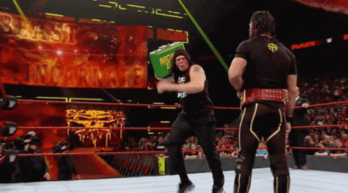 Two Men In A Wrestling Ring One Of Whom Is Holding A Green Box That Says Money In The Bank GIF