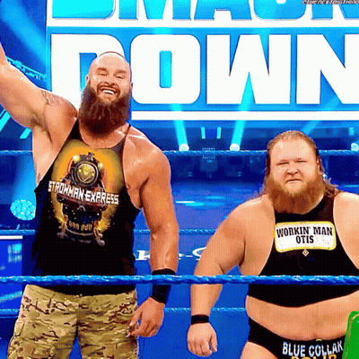 Two Men In A Wrestling Ring One Wearing A Shirt That Says Workin ' Man Otis GIF