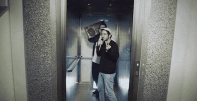 Two Men In An Elevator With One Holding A Boombox On His Shoulder GIF