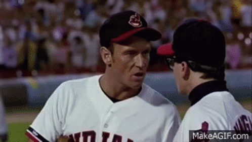 Two Men In Baseball Uniforms Are Talking To Each Other On A Field . GIF