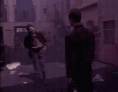Two Men In Black Jackets Standing In Dark Room GIF