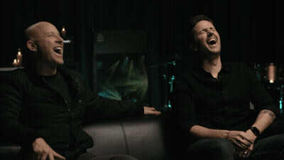 Two Men In Black Shirts Laughing Together GIF