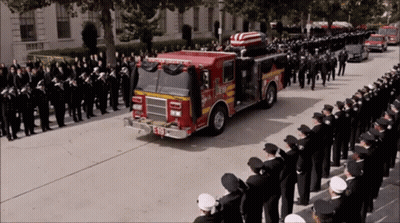 Two Men In Black Suits Dancing Around Coffin GIF