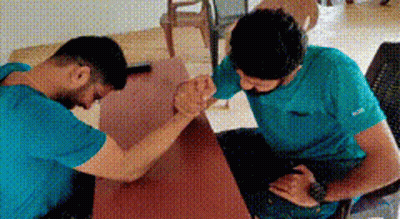 Two Men In Blue Shirts Arm Wrestling GIF