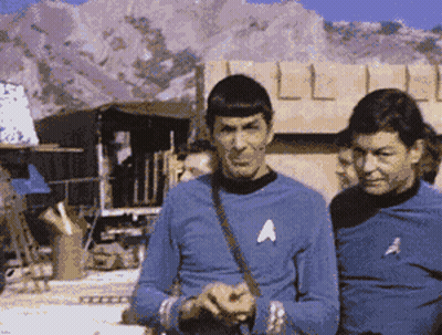 Two Men In Blue Shirts With A On Chests GIF