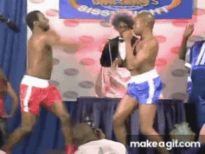 Two Men In Boxing Shorts Are Dancing In Front Of A Sign That Says ' Big ' On It GIF