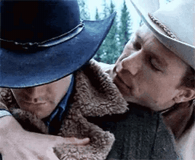 Two Men In Cowboy Hats Are Hugging Each Other . One Of The Men Is Wearing A Blue Hat . GIF