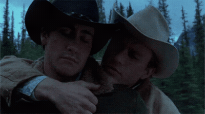 Two Men In Cowboy Hats Hugging Each Other In The Woods GIF