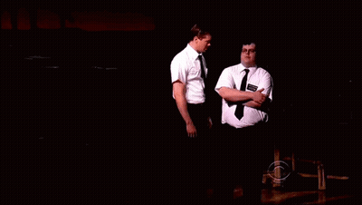Two Men In Dark Room One With Smith Name Tag GIF