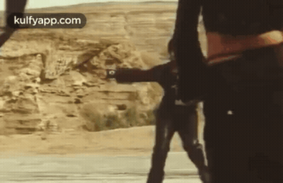 Two Men In Desert One Holding Gun GIF