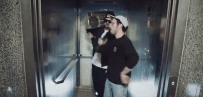 Two Men In Elevator One Wearing Hat And Sunglasses GIF