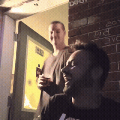 Two Men in Front of Brick Wall Saying Pig