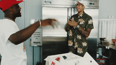 Two Men In Front Of Treats Sign GIF
