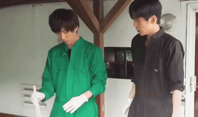 Two Men In Green Jumpsuits And White Gloves Are Standing Next To Each Other . GIF