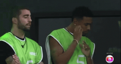 Two Men In Green Vests Are Standing Next To Each Other With Their Arms Crossed . GIF