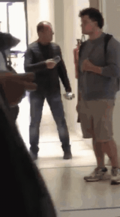 Two Men In Hallway One Holding Water Bottle GIF
