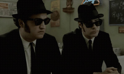 Two Men In Hats And Sunglasses Beside Coca Cola Chalkboard GIF