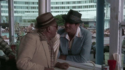 Two Men In Hats Sitting At Counter Talking GIF