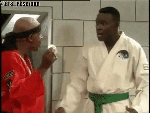 Two Men In Karate Uniforms Are Standing Next To Each Other . GIF