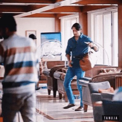 Two Men In Living Room With Tanuja Logo GIF
