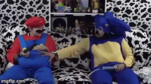 Two Men In Mario And Sonic Costumes Are Sitting On A Couch GIF