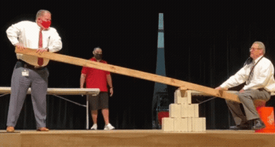Two Men In Masks Playing Seesaw GIF