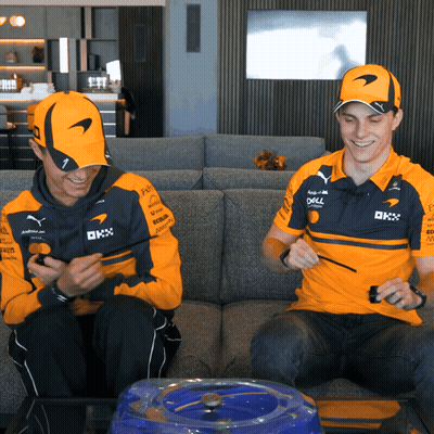 Two Men In McLaren Shirts On Couch Looking At Phones GIF