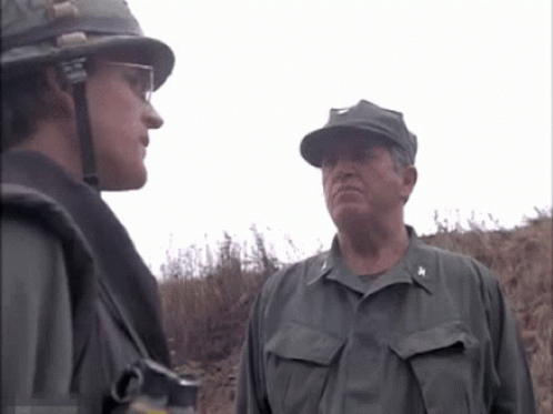 Two Men In Military Uniforms Are Standing Next To Each Other And One Has The Letter A On His Chest GIF