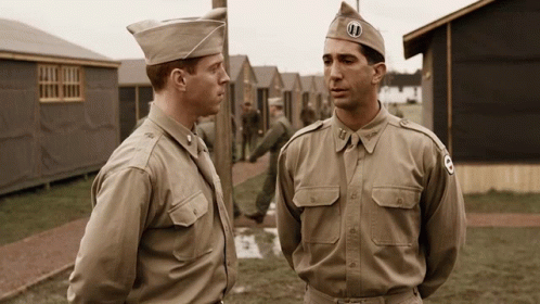 Two Men In Military Uniforms Are Standing Next To Each Other With One Wearing A Hat With The Letter Ui On It GIF
