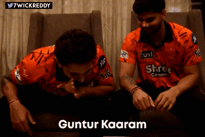 Two Men In Orange Shirts Are Sitting On A Couch And One Of Them Says Guntur Kaaram GIF