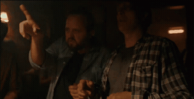 Two Men In Plaid Shirts Sitting Hands On Chests GIF