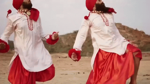 Two Men In Red And White Clothes Are Dancing In A Desert GIF