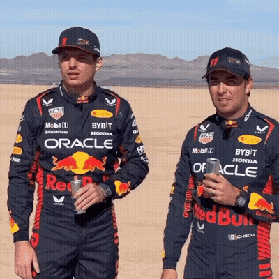 Two Men In Red Bull Racing Uniforms Standing In Desert GIF