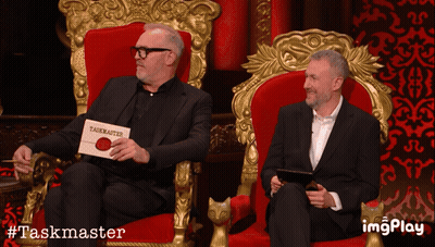 Two Men In Red Chairs With Taskmaster Sign GIF