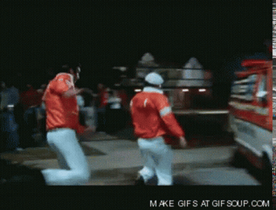 Two Men In Red Jackets Are Dancing In Front Of A Fire Truck That Says Make Gifs At Gif Soup.com GIF