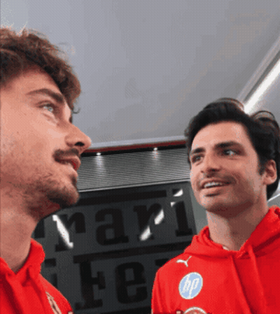 Two Men In Red Sweatshirts In Front Of Ferrari Sign GIF