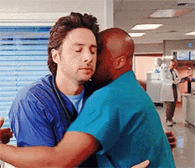 Two Men In Scrubs Hugging In A Hospital GIF