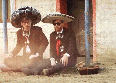 Two Men In Sombrero Hats Sitting On Ground GIF