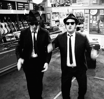 Two Men In Suits And Hats Dancing In Front Of Help Sign GIF