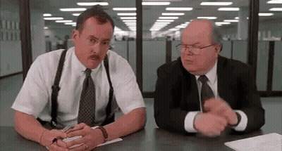 Two Men In Suits And Suspenders Are Sitting At A Table Talking To Each Other . GIF