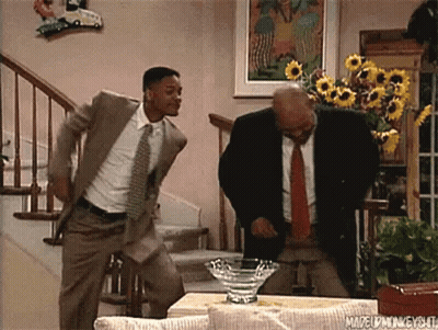 Two Men In Suits And Ties Are Dancing In A Living Room In Front Of Stairs . GIF