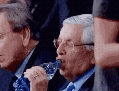 Two Men In Suits And Ties Are Drinking Water From A Bottle . GIF