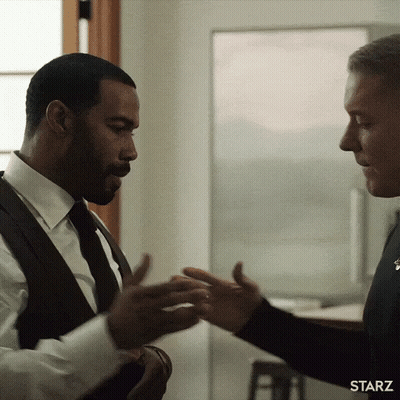 Two Men In Suits And Ties Are Shaking Hands In A Starz Advertisement . GIF