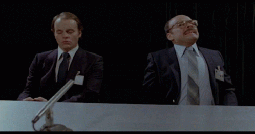 Two Men In Suits And Ties Are Sitting At A Desk With Microphones GIF