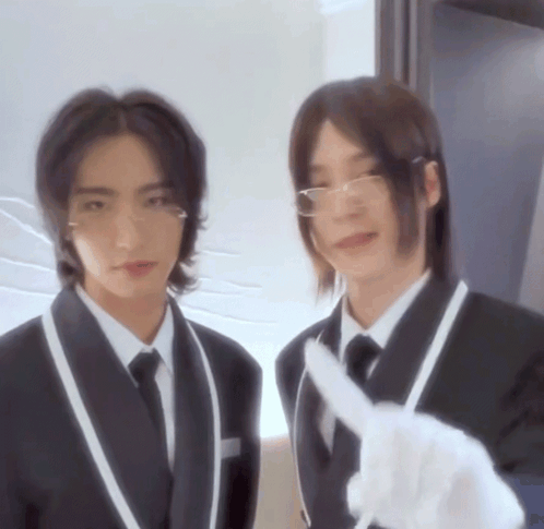 Two Men In Suits And Ties Are Standing Next To Each Other And One Is Pointing At The Camera GIF