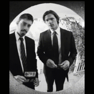 Two Men In Suits And Ties Are Standing Next To Each Other And One Of Them Has A Cbs Sticker On His Jacket GIF